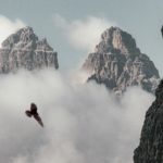 An eagle soaring high above the clouds between majestic mountains